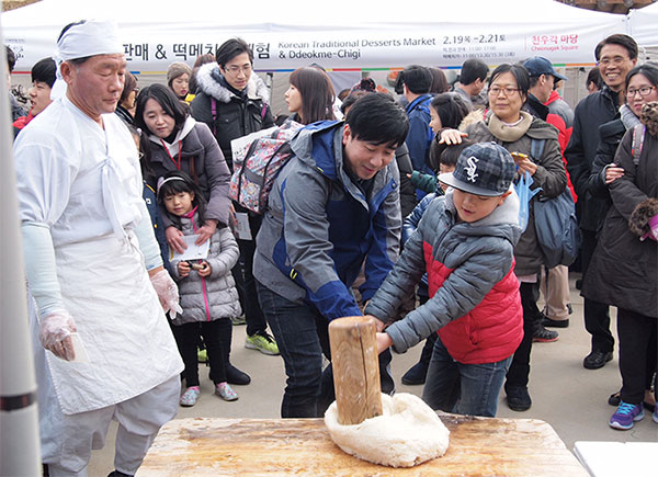 남산골한옥마을에서 떡메를 체험하는 사람들의 모습.